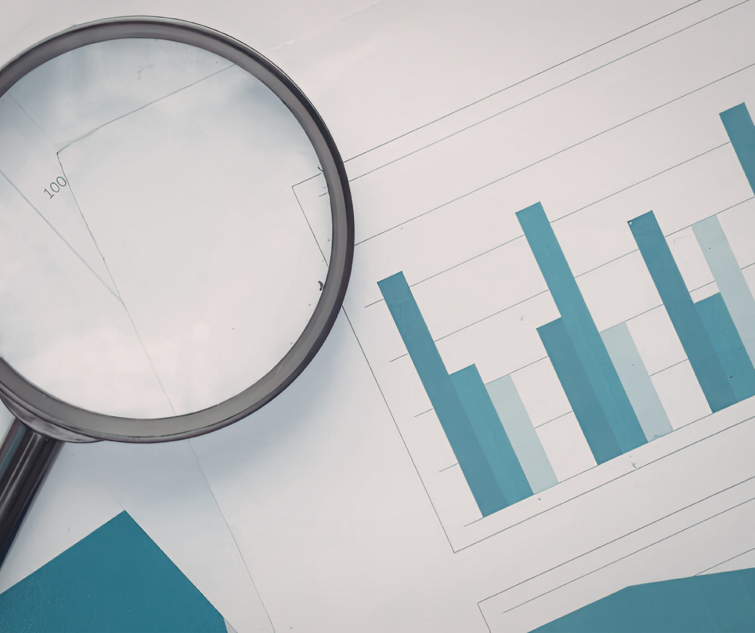 A magnifying glass is placed over papers displaying blue bar graphs and charts, suggesting data analysis and financial review.